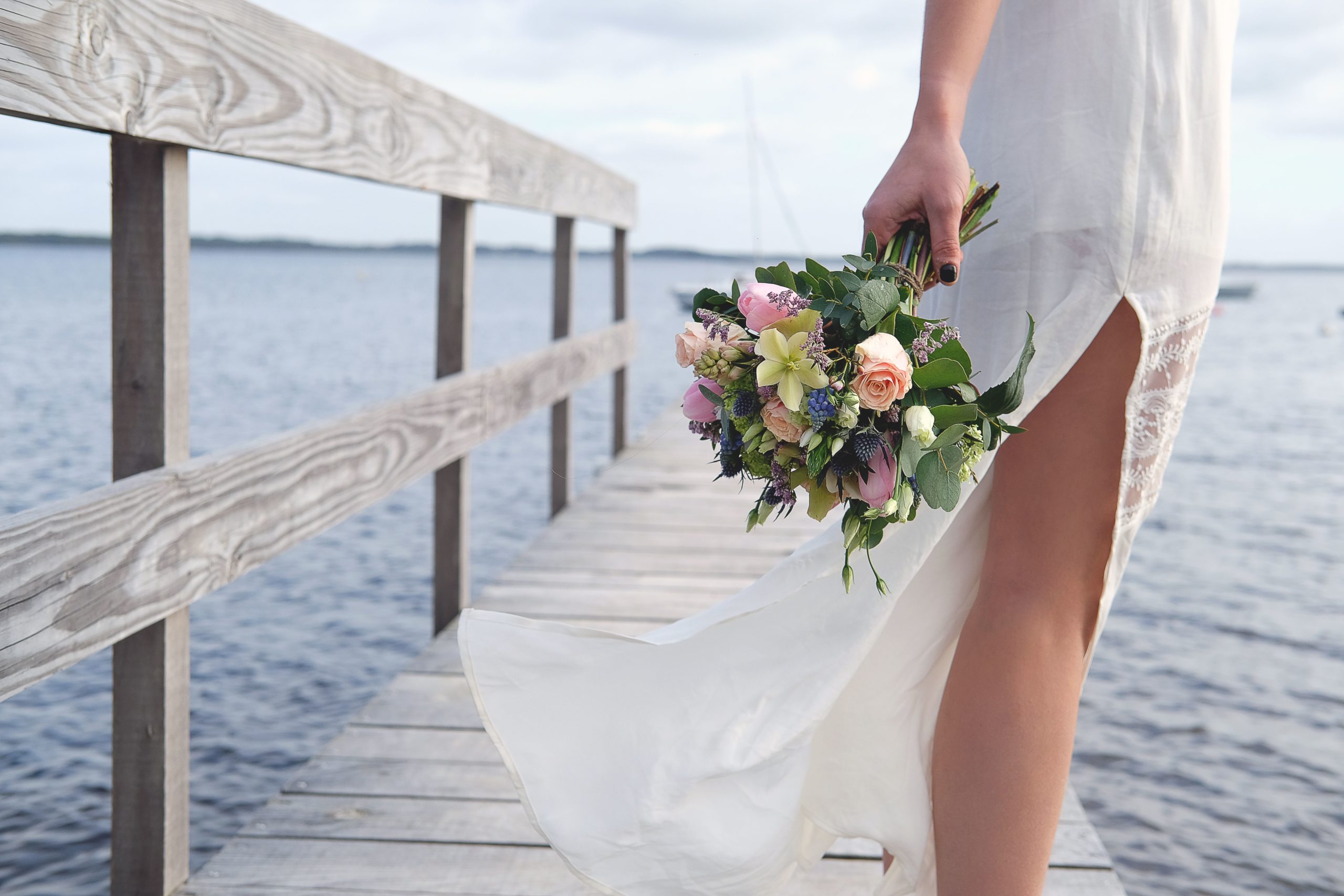 Une mariée pieds nus au bord de l'océan. Bouquet de mariée signée KRAFT fleurs et jouets